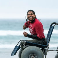 Jose smiles on the beach in a wheelchair.